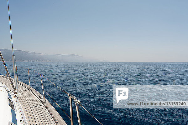 View of the side of a yacht and the Sardinian coast