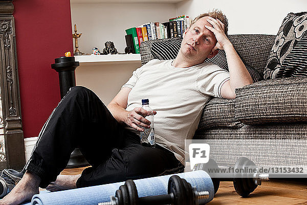 Mid adult man leaning against sofa resting from exercise