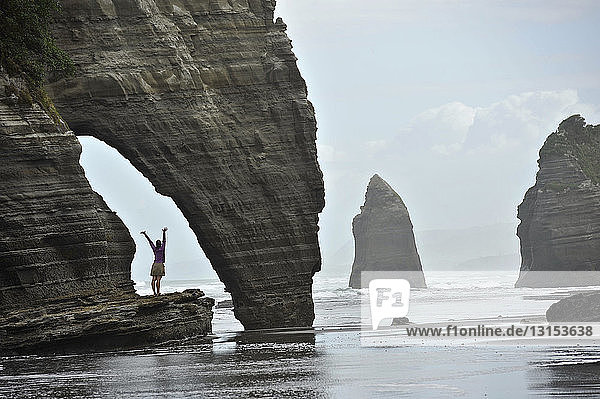 Junge Frau mit geöffneten Armen am Strand Felsformation  Nordinsel  Neuseeland