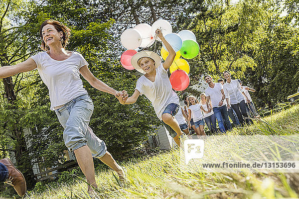 Eine Gruppe von Menschen läuft durch den Wald  ein Junge hält ein Bündel Luftballons