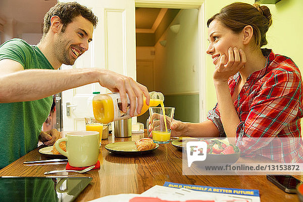 Young couple at breakfast  man pouring orange juice