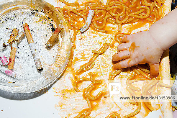 Baby greift nach Spaghetti am Aschenbecher