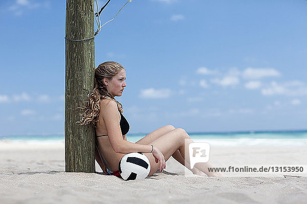 Young woman on beach with volleyball