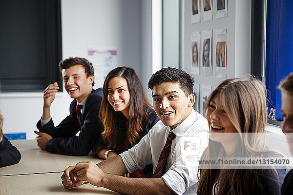 Teenage schoolchildren sitting at desks in classroom