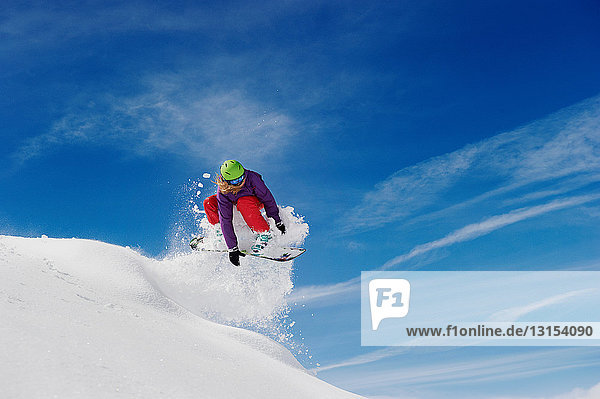 Frau beim Snowboarden  mitten in der Luft