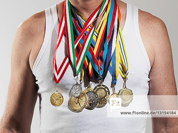 Mature man wearing gold medals against white background