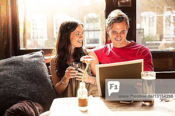 Couple enjoying drinks looking at newspaper together