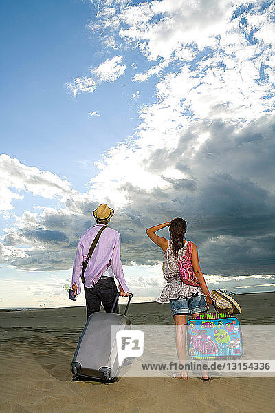 Traveling couple walk in sand