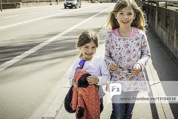 Zwei junge Mädchen gehen lächelnd gemeinsam die Straße entlang