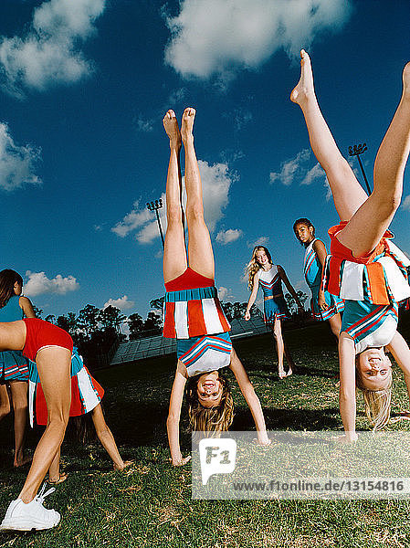 Cheerleader machen Handstand auf dem Spielfeld