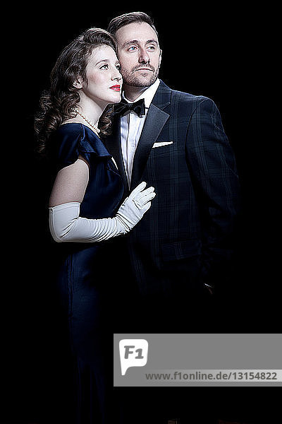 Mid adult couple in 1920's style dress against black background