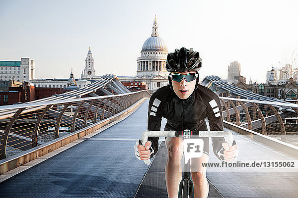 Cyclist cycling over Millennium Bridge  London  England