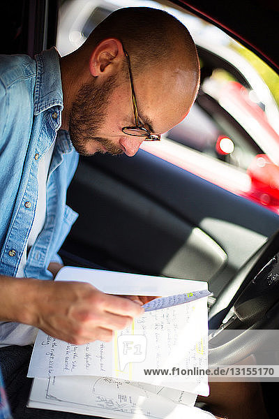 Mittlerer Erwachsener Mann liest Notizen im Auto