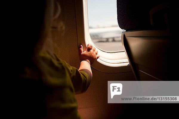 Kleiner Junge schaut durch ein Flugzeugfenster