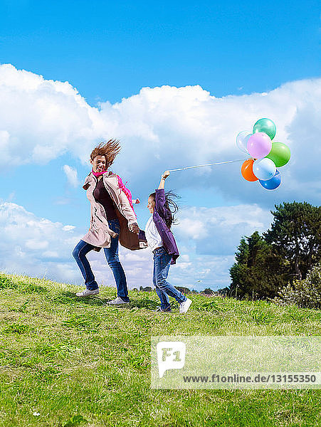 Mutter und Tochter mit Luftballons im Wind