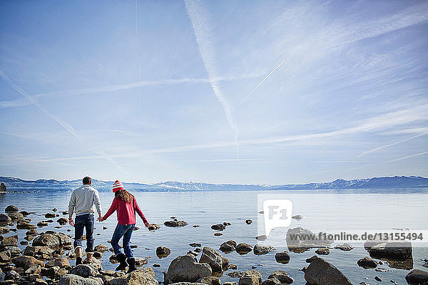 Paar geht auf Felsen in der Nähe des Sees