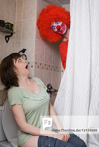 Clown erschreckt eine Frau auf der Toilette