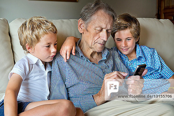 Großvater und Enkel schauen gemeinsam auf das Smartphone