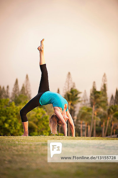 Woman practicing yoga in grassy field