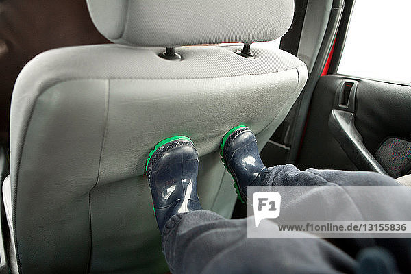 Füße des Kindes auf der Rückenlehne des Autositzes