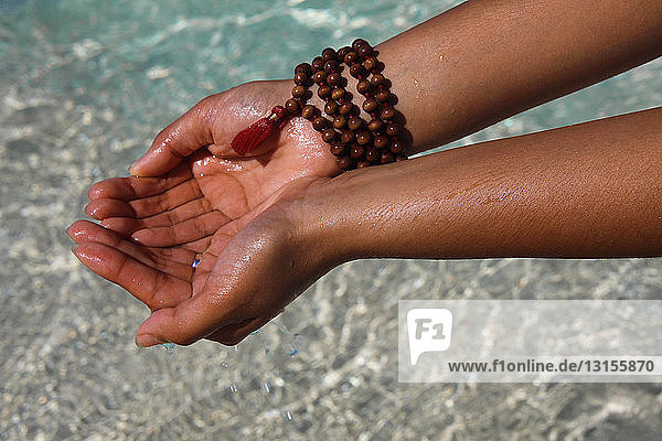 Nahaufnahme von Händen  die Wasser am Strand halten  Paradise Island  Nassau  Bahamas