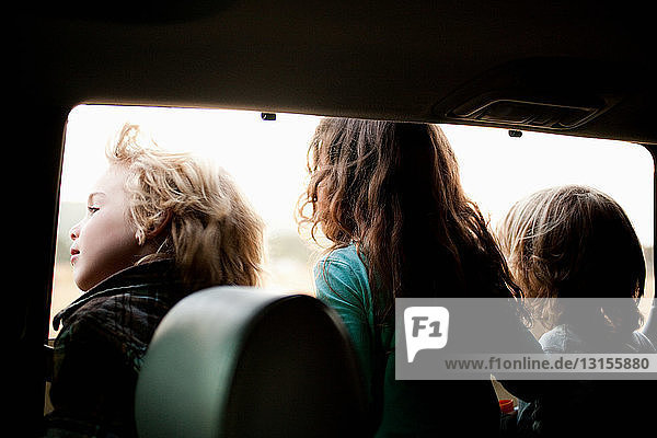 Drei Kinder schauen durch ein Autofenster