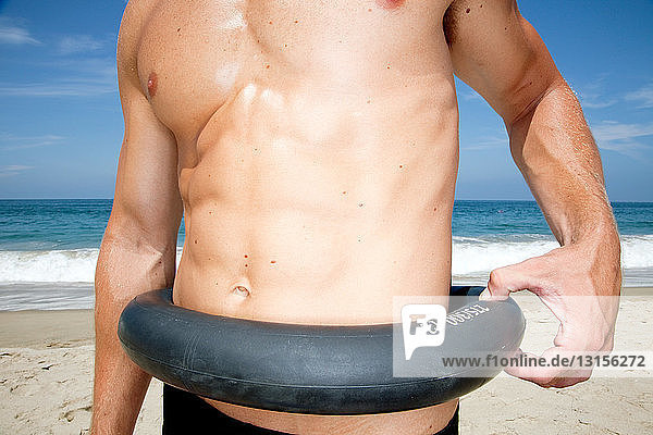 Mann am Strand klemmt Reifen um die Taille