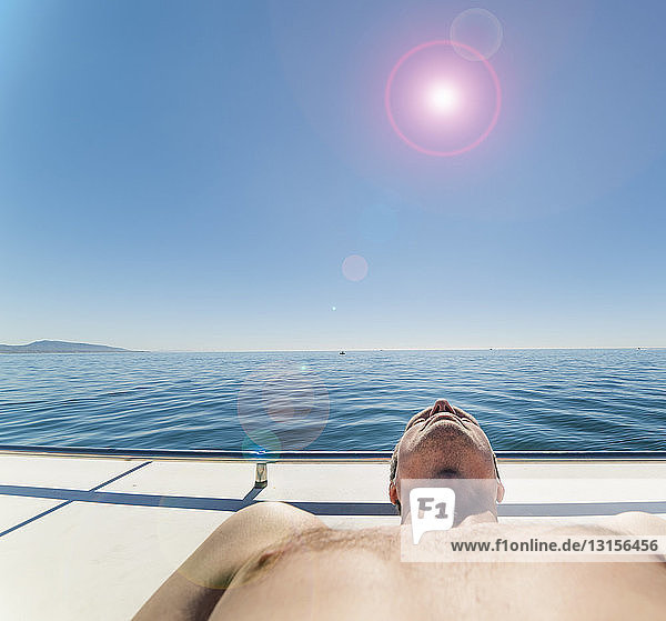 Mann auf Segelboot beim Sonnenbaden