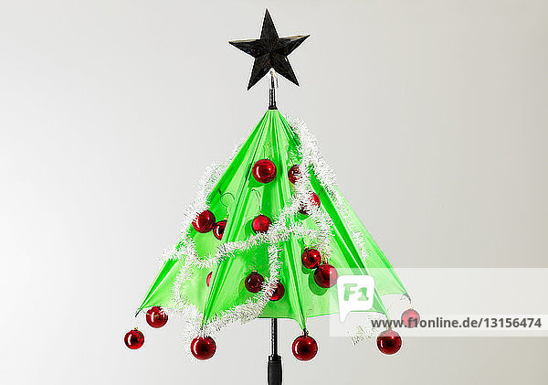 Green umbrella with Christmas decorations against white background