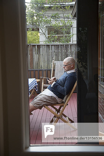 Mann telefoniert auf der Veranda
