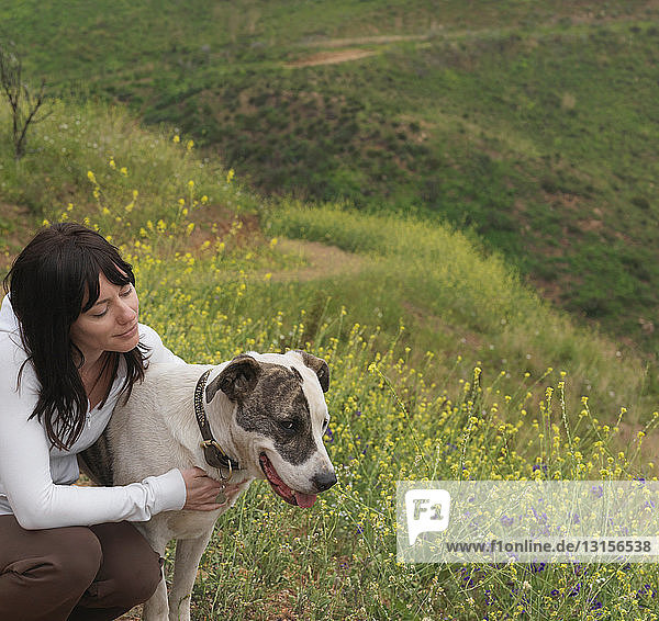 Frau umarmt Hund auf Naturlehrpfad