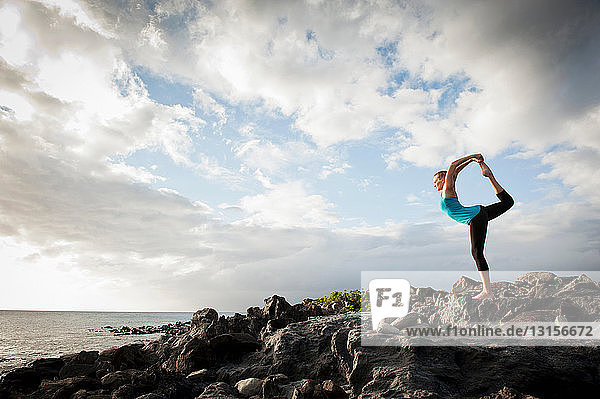 Woman practicing yoga on rock formation