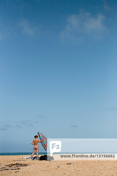 Frau hält Sonnenschirm am Strand