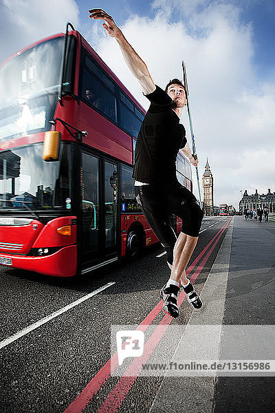 Javelin thrower on road with bus  London  England