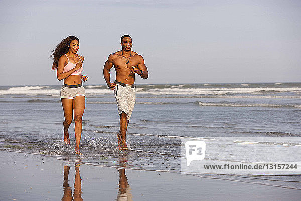 Paar läuft lächelnd am Strand entlang