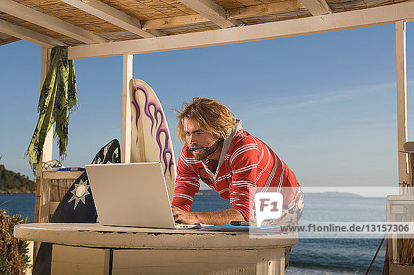junger Mann mit Laptop im Strandhaus