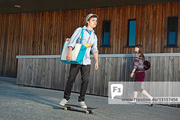 Junger Mann auf Skateboard mit Einkäufen