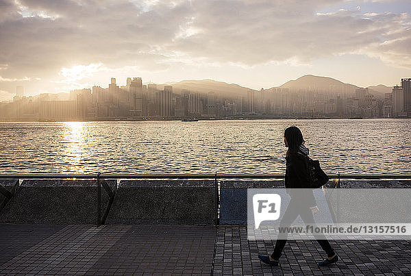 Side view of young woman walking past water  Hong Kong  China