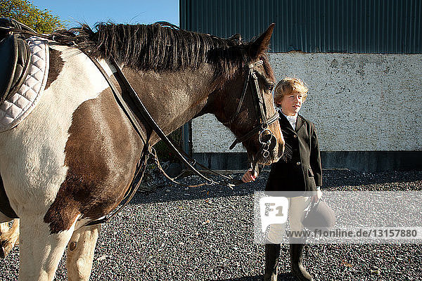 Junge hält Zügel eines Pferdes