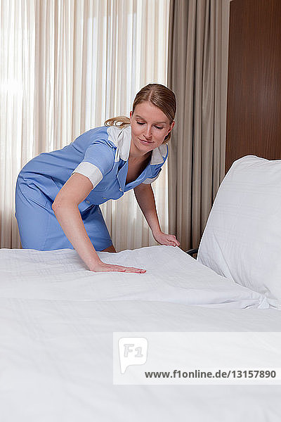 Zimmermädchen macht ein Bett im Hotelzimmer