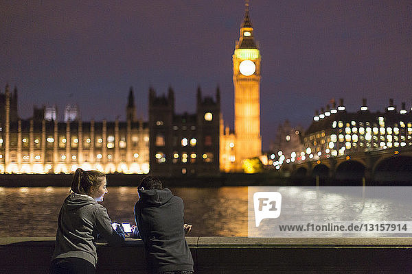 Rückansicht einer jungen Frau mit Smartphone gegenüber dem Palace of Westminster  London  UK