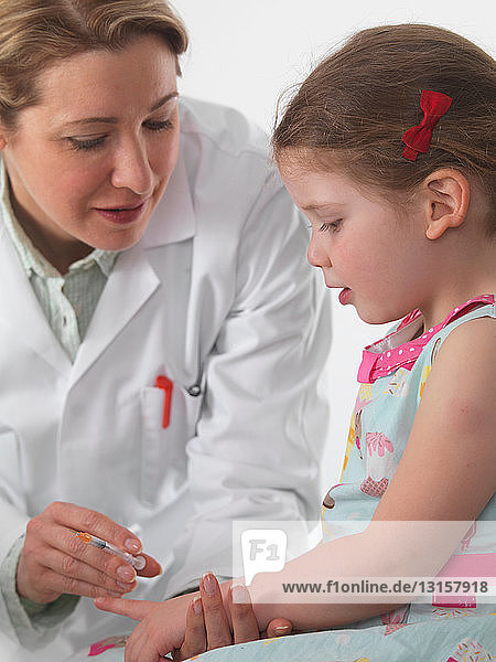 Allgemeinmediziner beim Impfen eines kleinen Mädchens in der Praxis