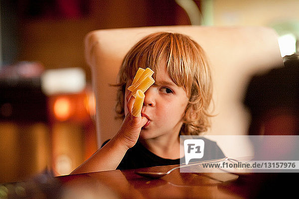 Junge isst Nudeln aus den Fingern
