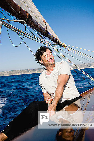 Mann lächelnd am Steuer eines Segelboots