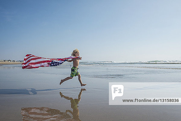 Junge läuft am Strand entlang  die Sternenflagge weht hinter ihm  Venice Beach  Kalifornien  USA