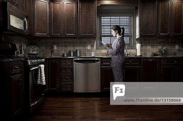 Frau in der Küche bei Nacht  mit digitalem Tablet