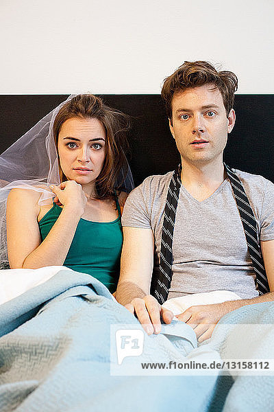 Portrait of young newlywed couple lying in bed