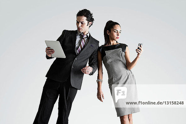 Man using digital tablet  woman on cell phone