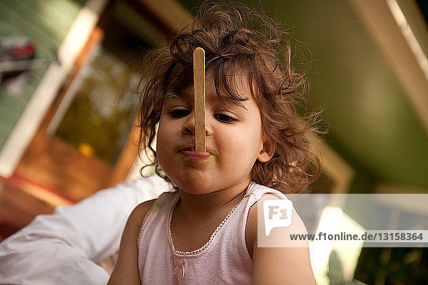 Young girl with ice lolly stick in mouth