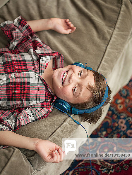 Junge entspannt sich auf dem Sofa und trägt Kopfhörer